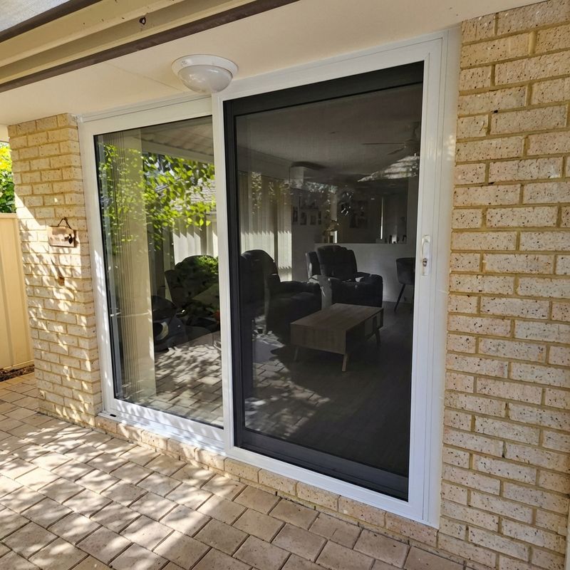 White-framed sliding door set in a brick wall